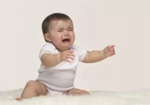 crying baby reaches out to be picked up