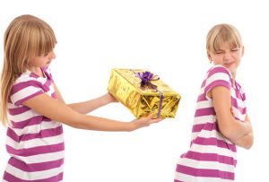 Young female trying to give a gift to her sister who is rejecting it. Studio isolated shot.